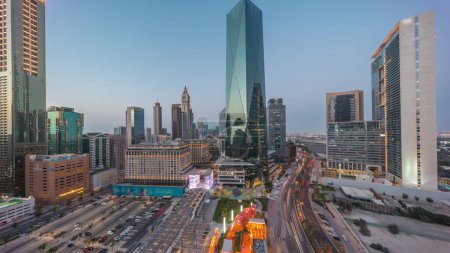 Téléchargez les photos : Dubai International Quartier financier transition jour-nuit. Vue aérienne panoramique du parking et des tours de bureaux d'affaires après le coucher du soleil. gratte-ciel avec hôtels et centres commerciaux près du centre-ville - en image libre de droit