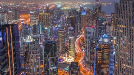 Foto de Skyline panoramic view of Dubai Marina and JBR showing canal surrounded by illuminated skyscrapers along shoreline aerial day to night transition . Traffic on curved road after sunset. DUBAI, UAE - Imagen libre de derechos