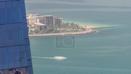 Téléchargez les photos : Partie de l'île Bluewaters avec une architecture moderne derrière un gratte-ciel en verre dans la marina aérienne de Dubaï. Bateaux flottant dans l'eau près de la zone JBR. - en image libre de droit