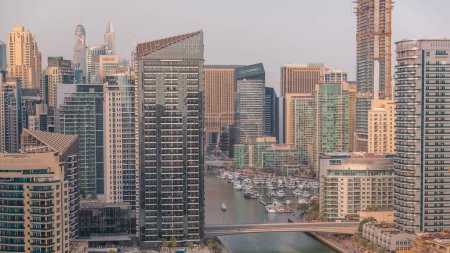 Téléchargez les photos : Dubai Marina avec plusieurs bateaux et yachts garés dans le port et gratte-ciel autour de l'antenne. Tours et pont sur le canal sur un fond - en image libre de droit