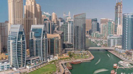 Téléchargez les photos : Dubai Marina avec plusieurs bateaux et yachts garés dans le port et gratte-ciel autour du canal aérien. Tours du quartier JBR avec des ombres se déplaçant rapidement - en image libre de droit