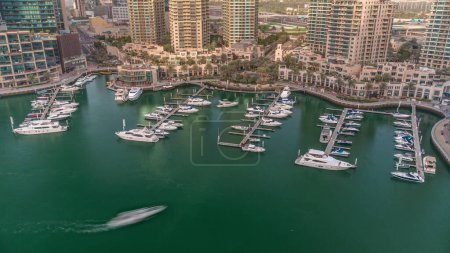 Foto de Barcos de lujo y yates atracados en Dubai Marina aérea. Barcos a motor estacionados a lo largo del muelle en el puerto cerca del paseo marítimo con fuente - Imagen libre de derechos