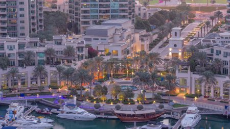 Téléchargez les photos : Picturesque fountain on Dubai Marina promenade aerial night to day transition  with palm around and yachts in harbor before sunrise - en image libre de droit