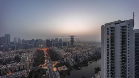 Foto de Skyscrapers in Barsha Heights district and low rise buildings in Greens district aerial night to day transition . Dubai panoramic skyline foggy morning - Imagen libre de derechos