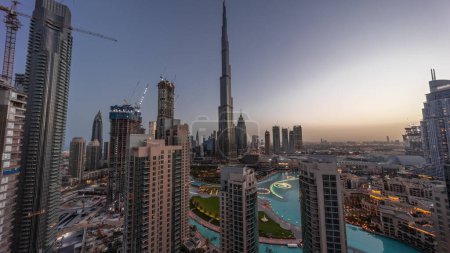Photo for Dubai Downtown cityscape with tallest skyscrapers around aerial night to day transition panoramic . Construction site of new towers and busy roads with traffic from above - Royalty Free Image