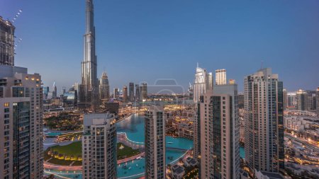 Foto de Dubai Centro de paisaje urbano con rascacielos más altos alrededor de la transición aérea día a noche después del atardecer. Sitio de construcción de nuevas torres y carreteras ocupadas con tráfico desde arriba - Imagen libre de derechos