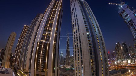 Téléchargez les photos : Panorama of tallest skyscrapers in downtown dubai located on bouleward street near shopping mall aerial day to night transition . Walking area with rooftop gardens after sunset - en image libre de droit