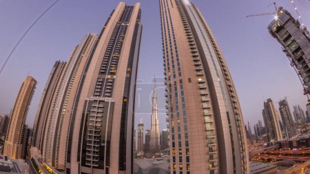 Téléchargez les photos : Panorama of tallest skyscrapers in downtown dubai located on bouleward street near shopping mall aerial night to day transition . Walking area with rooftop gardens before sunrise - en image libre de droit
