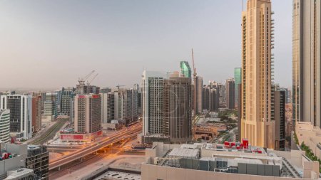 Photo for Skyscrapers at the Business Bay in Dubai aerial night to day transition . Road intersection and construction site of new towers with cranes before sunrise, United Arab Emirates - Royalty Free Image
