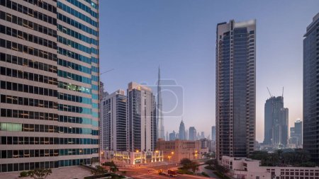 Foto de Aerial panoramic view to Dubai downtown and difc skyscrapers with busy traffic on intersection in Business bay district night to day transition  during sunrise. - Imagen libre de derechos