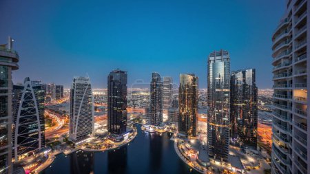 Foto de Edificios residenciales altos en el distrito JLT transición aérea día a noche, parte del distrito de uso mixto del centro de productos básicos de Dubai. Vista panorámica de torres y rascacielos - Imagen libre de derechos
