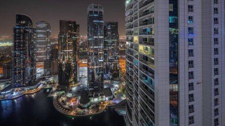 Téléchargez les photos : Panorama showing tall residential buildings at JLT district aerial night , part of the Dubai multi commodities centre mixed-use district. Illuminated towers and skyscrapers - en image libre de droit