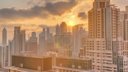 Foto de Dubai skyscrapers with golden sunset over business bay district . Aerial view from of downtown in United Arab Emirates. Colorful clouds and sun beams - Imagen libre de derechos