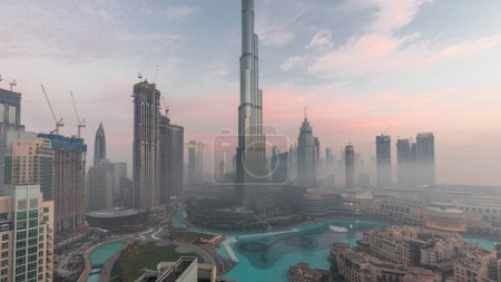 Téléchargez les photos : Aerial view of Dubai city early morning during fog night to day transition . Futuristic city panoramic skyline with skyscrapers and towers from above - en image libre de droit
