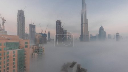 Photo for Aerial view of Dubai city early morning during fog night to day . Futuristic city skyline with skyscrapers and towers under construction from above - Royalty Free Image