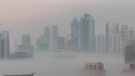Téléchargez les photos : Dubai skyscrapers with morning fog in business bay district night to day transition . Aerial view from top of downtown in United Arab Emirates. - en image libre de droit
