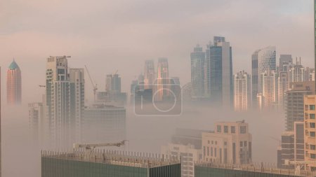 Photo for Dubai skyscrapers covered by morning fog in business bay district during sunrise . Aerial view from top of downtown in United Arab Emirates. - Royalty Free Image