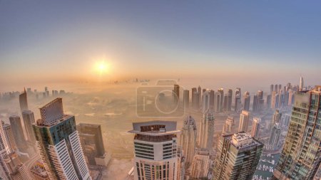 Photo for Panorama of Dubai Marina with JLT skyscrapers and golf course during sunrise , Dubai, United Arab Emirates. Aerial view from above towers foggy morning. City skyline with rooftops - Royalty Free Image