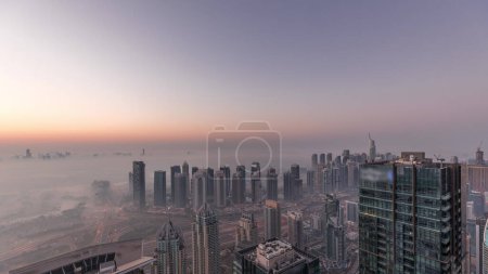 Téléchargez les photos : Panorama of Dubai Marina with JLT skyscrapers and golf course night to day transition , Dubai, United Arab Emirates. Aerial view from above towers foggy morning. City skyline with rooftops - en image libre de droit