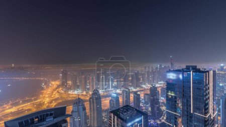 Photo for Panorama of Dubai Marina with JLT skyscrapers and golf course during all night , Dubai, United Arab Emirates. Aerial view from above towers with fog. City skyline with lights turning off - Royalty Free Image