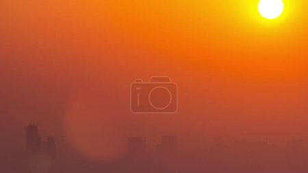 Téléchargez les photos : Sunrise close up view over Dubai skyline in the morning, aerial top view from Dubai marina . Big sun on orange sky rise over fog around skyscrapers. United Arab Emirates - en image libre de droit
