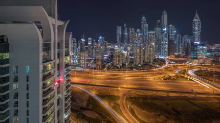 Foto de Panorama of Dubai Marina showing highway intersection spaghetti junction night . Illuminated tallest skyscrapers on a background. Aerial top view from JLT district. - Imagen libre de derechos
