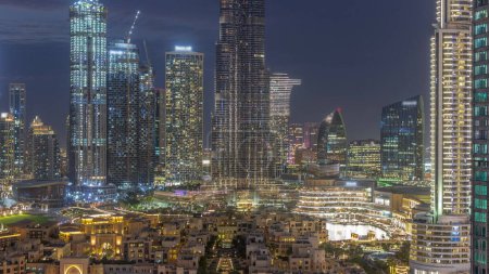 Foto de Dubai Downtown Transición día a noche con rascacielos más altos y otras torres alrededor del casco antiguo y la fuente después del atardecer en Dubai, Emiratos Árabes Unidos. Luces encendidas. - Imagen libre de derechos