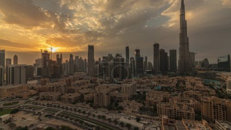 Téléchargez les photos : Sunset over Dubai Downtown  with tallest skyscraper and other towers view from the top in Dubai, United Arab Emirates. Rays of light and cloudy orange sky - en image libre de droit