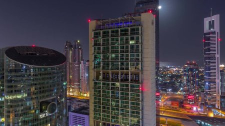 Foto de Dubai centro financiero internacional rascacielos aéreos durante toda la noche. Torres iluminadas con luces apagando la vista desde arriba. Luna poniéndose - Imagen libre de derechos