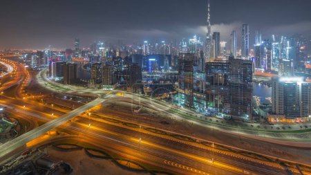 Foto de Skyline panorámico de tráfico ocupado en al khail carretera en Dubai con la bahía de negocios y el centro de distrito durante toda la noche. Vista aérea de muchos rascacielos modernos. Emiratos Árabes Unidos. - Imagen libre de derechos