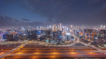 Téléchargez les photos : Skyline panoramique de Dubaï avec la baie d'affaires et le quartier du centre-ville et la circulation sur al khail road night. Vue aérienne de nombreux gratte-ciel modernes avec des nuages colorés après le coucher du soleil. Émirats arabes unis. - en image libre de droit