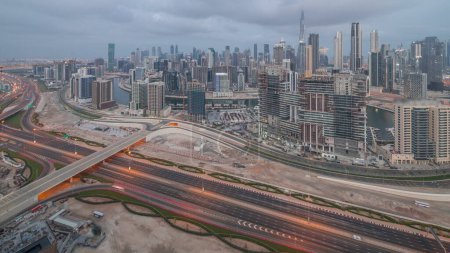 Téléchargez les photos : Skyline panoramique de Dubaï avec baie d'affaires et quartier du centre-ville la nuit avec la circulation sur la route al khail. Vue aérienne de nombreux gratte-ciel et chantiers de construction modernes avant le lever du soleil. Émirats arabes unis - en image libre de droit