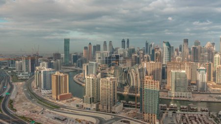 Téléchargez les photos : Skyline avec l'architecture moderne de Dubai tours de baie d'affaires matin. Vue panoramique aérienne avec canal et chantier pendant le lever du soleil avec ciel nuageux - en image libre de droit