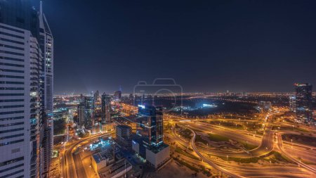 Foto de Vista panorámica aérea de la ciudad de los medios de comunicación y la zona del distrito de alturas al barsha durante toda la noche desde el puerto deportivo de Dubái con luces apagadas. Torres y rascacielos con tráfico en una carretera desde arriba - Imagen libre de derechos
