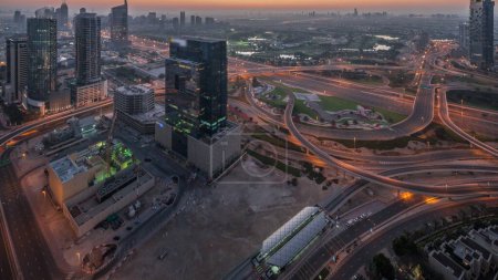 Téléchargez les photos : Aerial panoramic view of media city and al barsha heights district with golf course night from Dubai marina during sunrise. Towers and skyscrapers with traffic on a highway crossroad from above - en image libre de droit