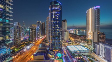 Foto de Panoramic view of the Dubai Marina and JBR area and the famous Ferris Wheel aerial day to night transition . Golden sand beaches in the Persian Gulf after sunset - Imagen libre de derechos