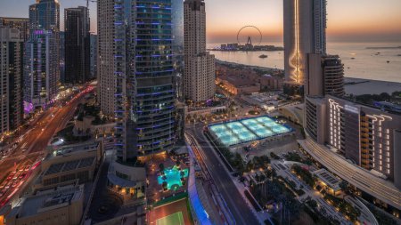 Téléchargez les photos : Vue panoramique sur la marina de Dubaï et la région de JBR et la célèbre transition de jour à nuit de la grande roue. Plages de sable doré dans le golfe Persique avec coucher de soleil - en image libre de droit