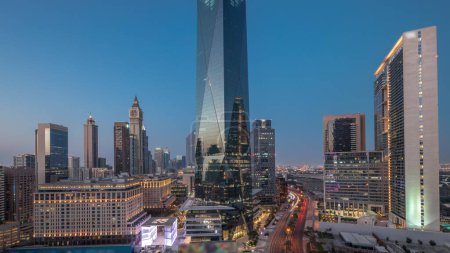 Téléchargez les photos : Dubai International Quartier financier transition jour-nuit. Vue aérienne panoramique des tours de bureaux d'affaires après le coucher du soleil. gratte-ciel avec hôtels et centres commerciaux près du centre-ville - en image libre de droit