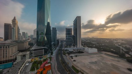 Foto de Sunrise in Dubai International Financial district transition . Panoramic aerial view of business office towers at morning. Skyscrapers with hotels and shopping malls near downtown - Imagen libre de derechos