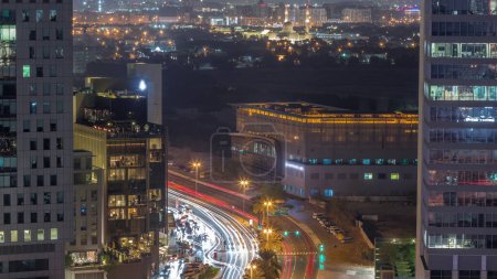 Foto de Vista panorámica del tráfico en la calle Al Saada cerca del distrito DIFC durante la noche y el distrito Deira en un segundo plano en Dubai, Emiratos Árabes Unidos. Rascacielos en vista aérea del centro financiero desde arriba. Ventanas brillantes - Imagen libre de derechos