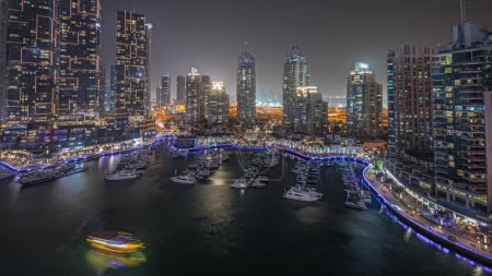 Foto de Panorama showing luxury yacht bay in the city aerial night  in Dubai marina. Modern skyscrapers along waterfront promenade and boats floating in harbor - Imagen libre de derechos