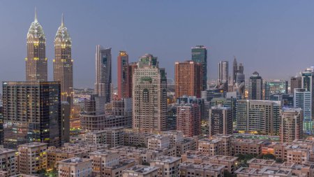 Téléchargez les photos : Des gratte-ciels dans le quartier de Barsha Heights et des immeubles de faible hauteur dans le quartier des Verts transition aérienne de jour à nuit. Skyline de Dubaï avec des tours de ville internet - en image libre de droit