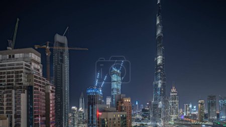 Photo for Panorama showing aerial cityscape night  with illuminated architecture of Dubai downtown. Many tall skyscrapers and towers with glowing windows. New construction site. - Royalty Free Image