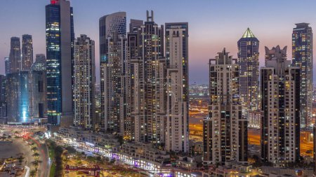 Téléchargez les photos : Bay Avenue avec des tours modernes développement résidentiel dans Business Bay transition aérienne de jour à la nuit, Dubaï, EAU. Gratte-ciel après le coucher du soleil - en image libre de droit