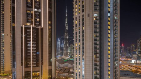 Téléchargez les photos : Panorama showing tallest skyscrapers during Earth hour in downtown dubai located on bouleward street near shopping mall aerial night . Lights and illumination turning on after one hour - en image libre de droit