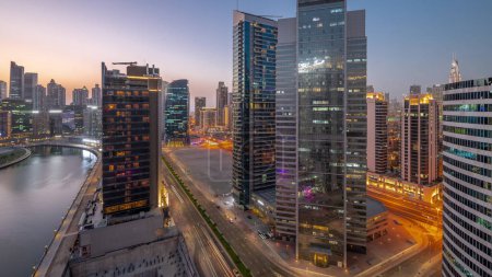Foto de Paisaje urbano de rascacielos en Dubai Business Bay y el centro de la ciudad con el canal de agua de día aéreo a la transición nocturna. skyline moderno con torres y paseo marítimo después de la puesta del sol. Un centro de negocios internacionales - Imagen libre de derechos