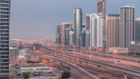 Foto de Dubai Marina skyscrapers and Sheikh Zayed road with metro railway aerial night to day transition . Traffic on a highway near modern towers before sunrise, United Arab Emirates - Imagen libre de derechos