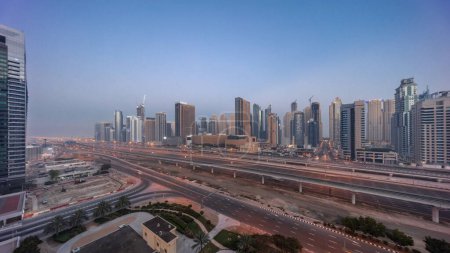 Photo for Dubai Marina skyscrapers and Sheikh Zayed road with metro railway aerial night to day transition panoramic . Traffic on a highway near modern towers before sunrise, United Arab Emirates - Royalty Free Image