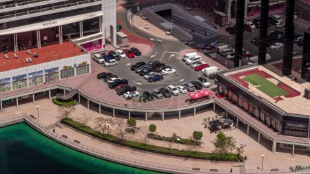 Téléchargez les photos : Parking au bord de l'eau vue d'en haut toute la journée, vue aérienne. Vue de dessus des véhicules stationnés près de l'immeuble de bureaux dans le quartier JLT de Dubaï. Ombres se déplaçant rapidement - en image libre de droit
