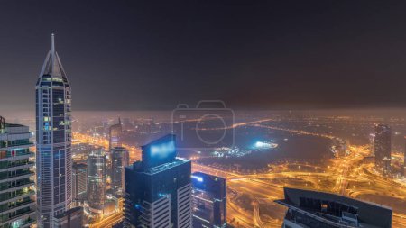 Téléchargez les photos : Aerial skyline with Golf Club, hotels and residential areas far away in desert in Dubai during all night  with fog, UAE, top view from Dubai marina skyscrapers. Lights turning off - en image libre de droit